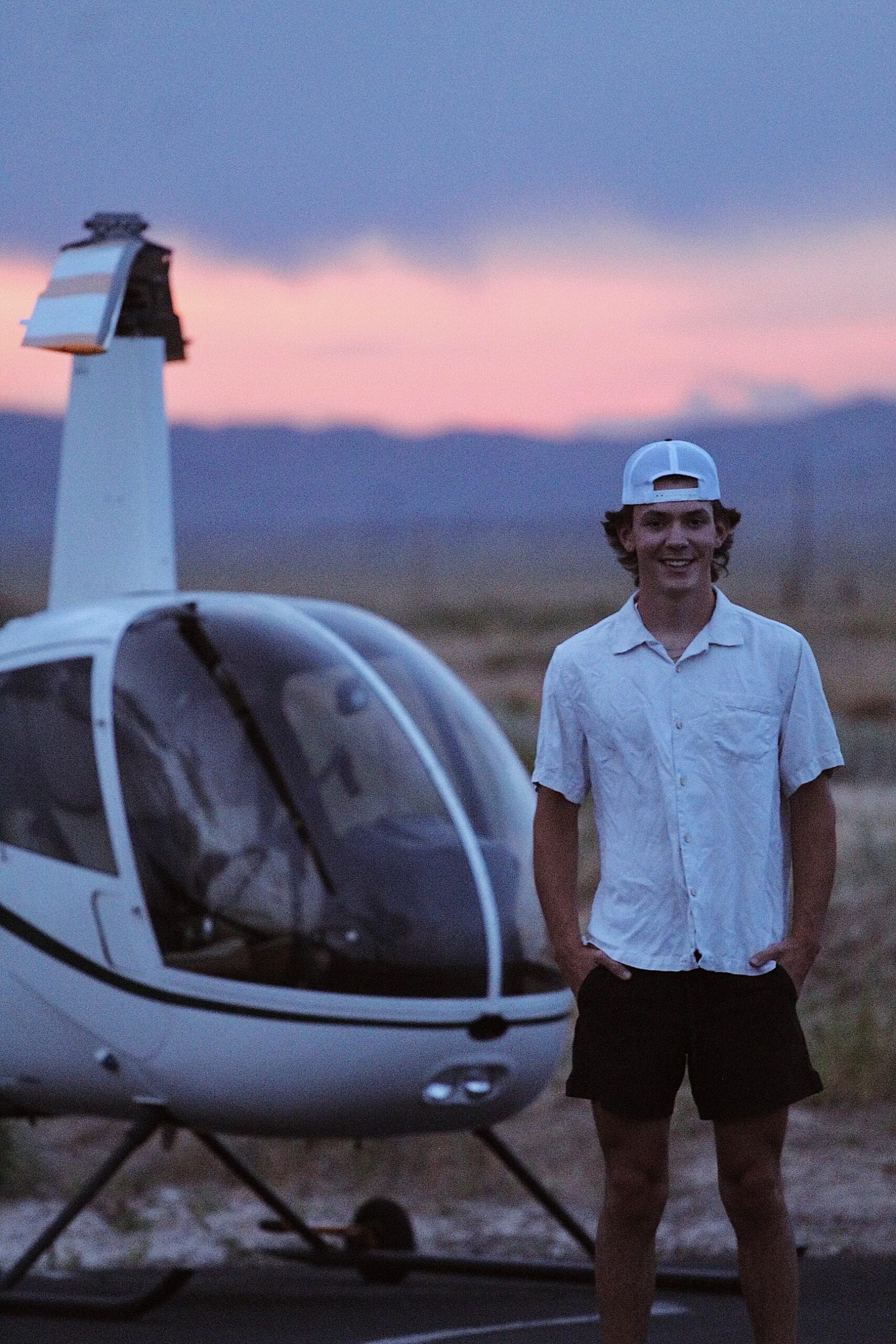 Pilot beside a helicopter at dusk